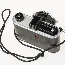 Black camera with metal trim. Wrist strap. Top view.