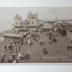 People on pier with building topped by cupolas.
