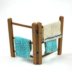 Upright wooden towel rack, with three towels.