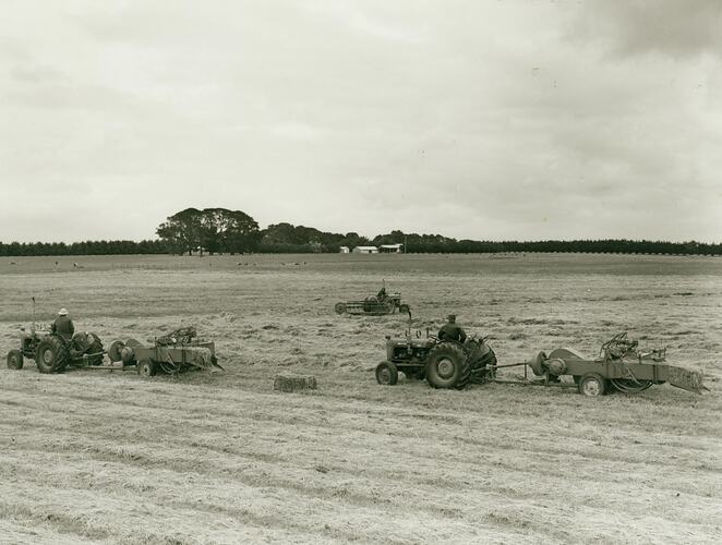 Tractors and balers in field collecting hay.
