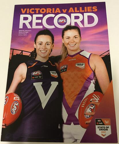 Booklet cover with two female footballers. One wears a navy jumper with a V, the other a red one with purple/w