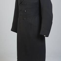 Gentleman's black cotton frock coat, six-button, double-breasted with peaked lapels.