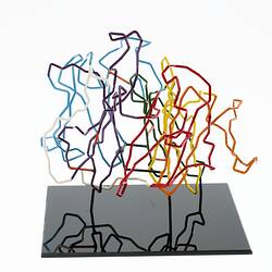 Red, orange, yellow, green, blue, purple and white coloured wires mounted on a black wooden base.