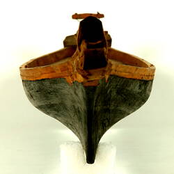 Wooden boat with black hull, front view.