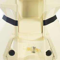 Detail of cream plastic robot with angular human-like shape, ie. head, shoulders, waist and legs. Black plastic features.