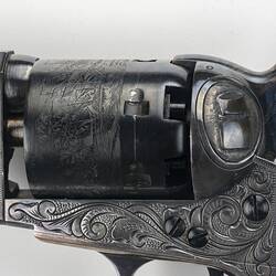 Engraved revolver with wooden handle. Detail of barrel and lever.