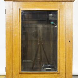 Detail of wooden clock base with central glass panel.