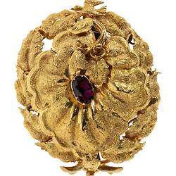 Gold oval locket brooch. Vine leaves and tendrils border. Branches at base with a small bird at top, all supporting a large flower with an amethyst purple paste stone centre.