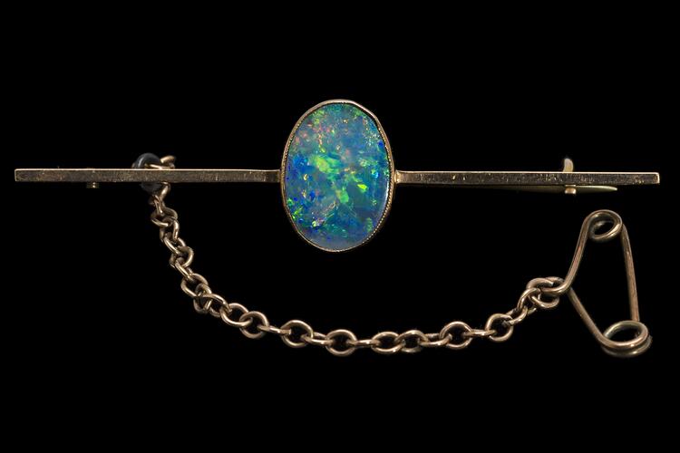 Gold bar brooch with central oval opal. Fine saftey chain attached at left.