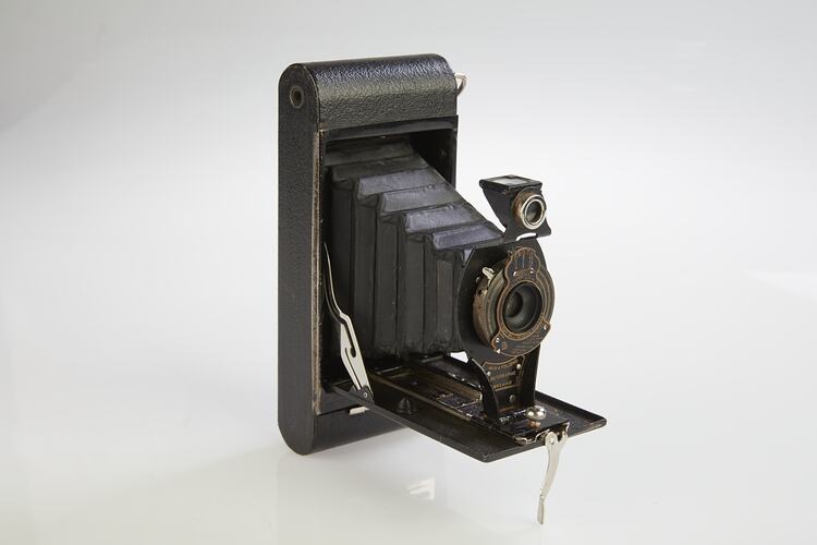 Folding camera with black leatherette covering. Central lens at front. Three quarter right view.