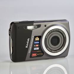Black and grey camera with metal trim on back, sides and around the lens. Three quarter view.