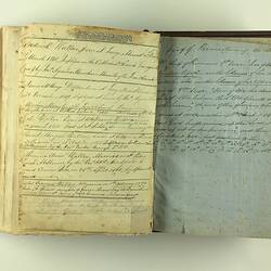 Open bible with white pages, both with handwritten cursive text. Small section of printed text on left page.