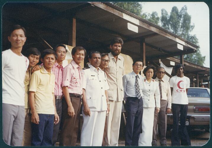 Group of men pose out the front of a building.