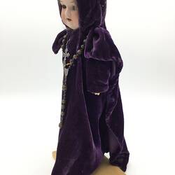 A doll dressed as an abbess in long purple robes