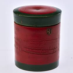 Red painted, cylindrical wooden box. Dark green trim around lid and base.