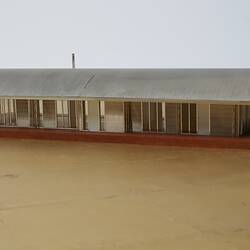 Model of a house with an arched roof, corrugated iron and wide expanses of glass.