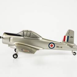 Model aeroplane, silver with black propeller and wheels. Red, white, blue roundels on wings, body and flag on tail. Left profile.