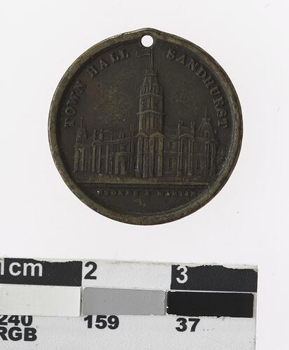 Round medal with building, text above and below.
