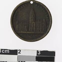 Round medal with building, text above and below.
