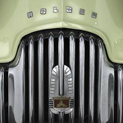 Detail of Holden car chrome grille with badge and cream bonnet.