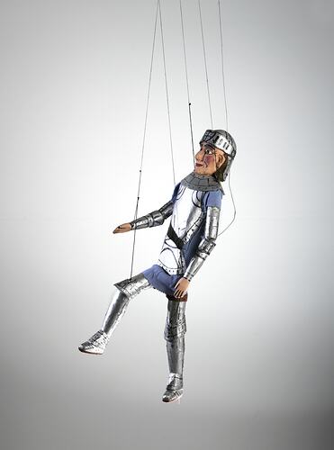 Left view of male marionette in silver armour.