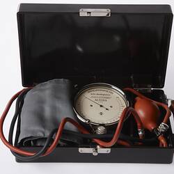 Medical equipment with cuff, dial and pump for measuring blood pressure.