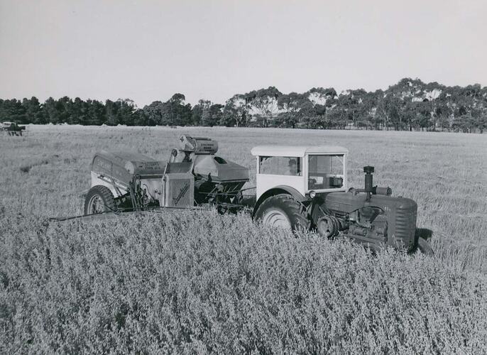 Man driving a tractor coupled to a Header Harvester.