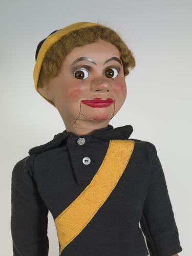 Ventriloquist doll in a black and yellow football jumper.