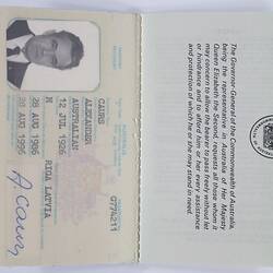 Passport, white pages and black print, blue signature, black and white photograph of a man.