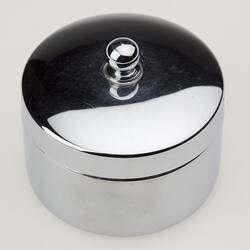 Round silver powder container with lid.