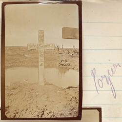 Cross covered in writing with puddle and barren landscape behind.