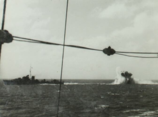 Military battleship on left, underwater explosion on right.