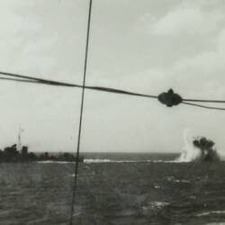 Military battleship on left, underwater explosion on right.