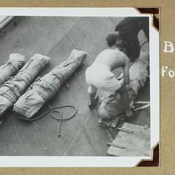 Four sailors preparing and wrapping four bodies wrapped in cloth, rope and belts.