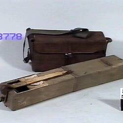 Periscope lying next to leather bag.