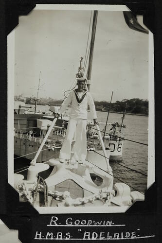 Man in Navy uniform standing on bow of ship.