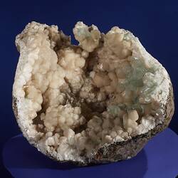 Rounded rock filled with cream and green crystals.