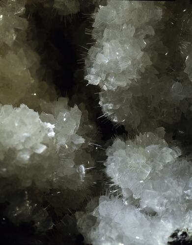 Clear-white blocky mineral with needle-like crystal protrusions.