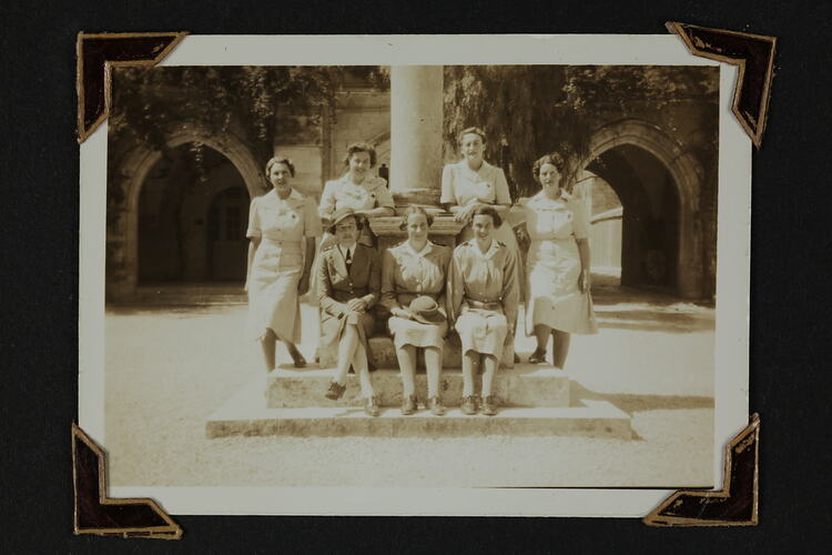 Seven woman in uniform around a pillar.