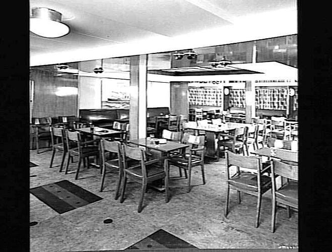 Ship interior. Sitting area with wooden chairs around tables.