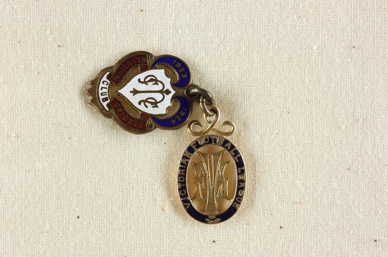 Ornate oval and circular gold and enamel medals attached by curled loop.