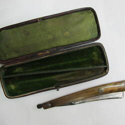 Cut-throat razor next to green-lined box, open