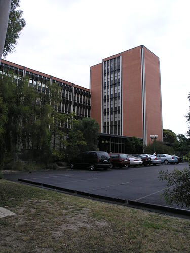Multistorey brick building with carpark in foreground.