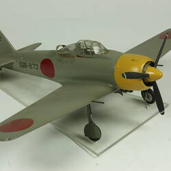 Green grey plane model with red spot on each wing and fusleage. Yellow nose, black propeller.