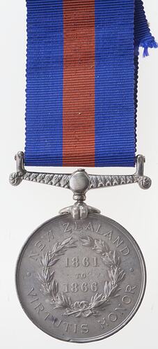 Round silver medal with text and blue and red ribbon attached.