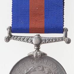 Round silver medal with text and blue and red ribbon attached.