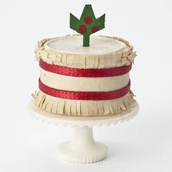 Miniature white with red bands cake from a doll's house.
