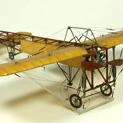 Model aeroplane with exposed wooden frame and off white panelling.