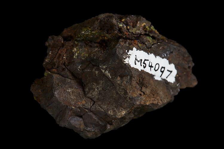 Brown rock with red, orange and green surface coating.