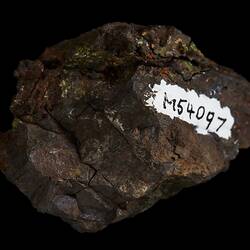 Brown rock with red, orange and green surface coating.